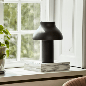 Modern black PC table lamp on books by a window, stylish home decor lighting solution, ambient light.