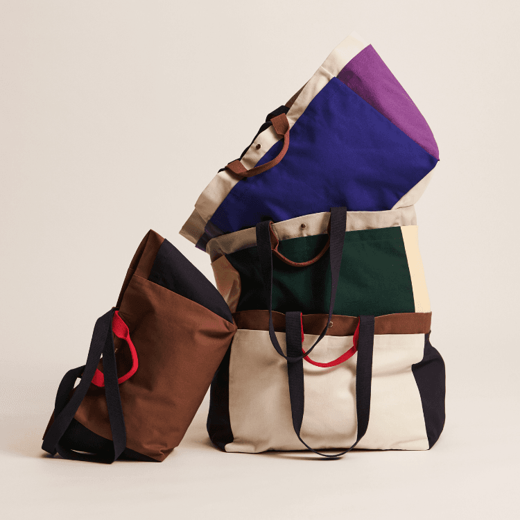 Stacked weekend bags in assorted colors. Stylish travel totes for short trips and getaways.
