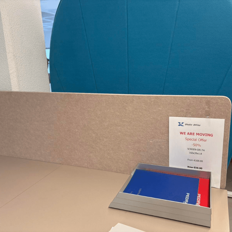 A beige office partition is on a desk next to a flyer and a metal document holder with blue and red papers.