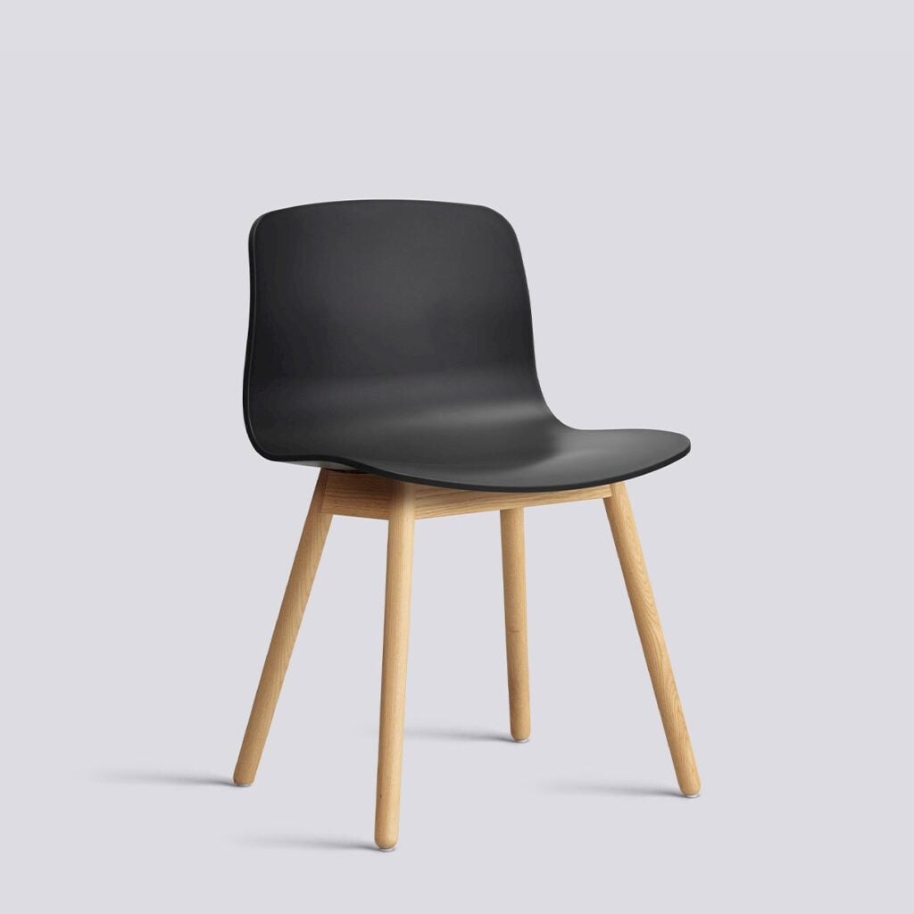 Black molded plastic chair with a curved seat and light wood legs on a plain background.