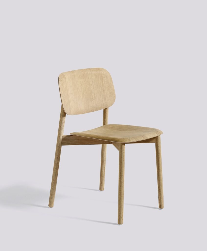 Light wood dining chair with curved backrest and seat, standing on four tapered legs against a plain grey background.